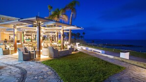 Cómoda zona de estar al aire libre con muebles de mimbre y vista al océano al anochecer.