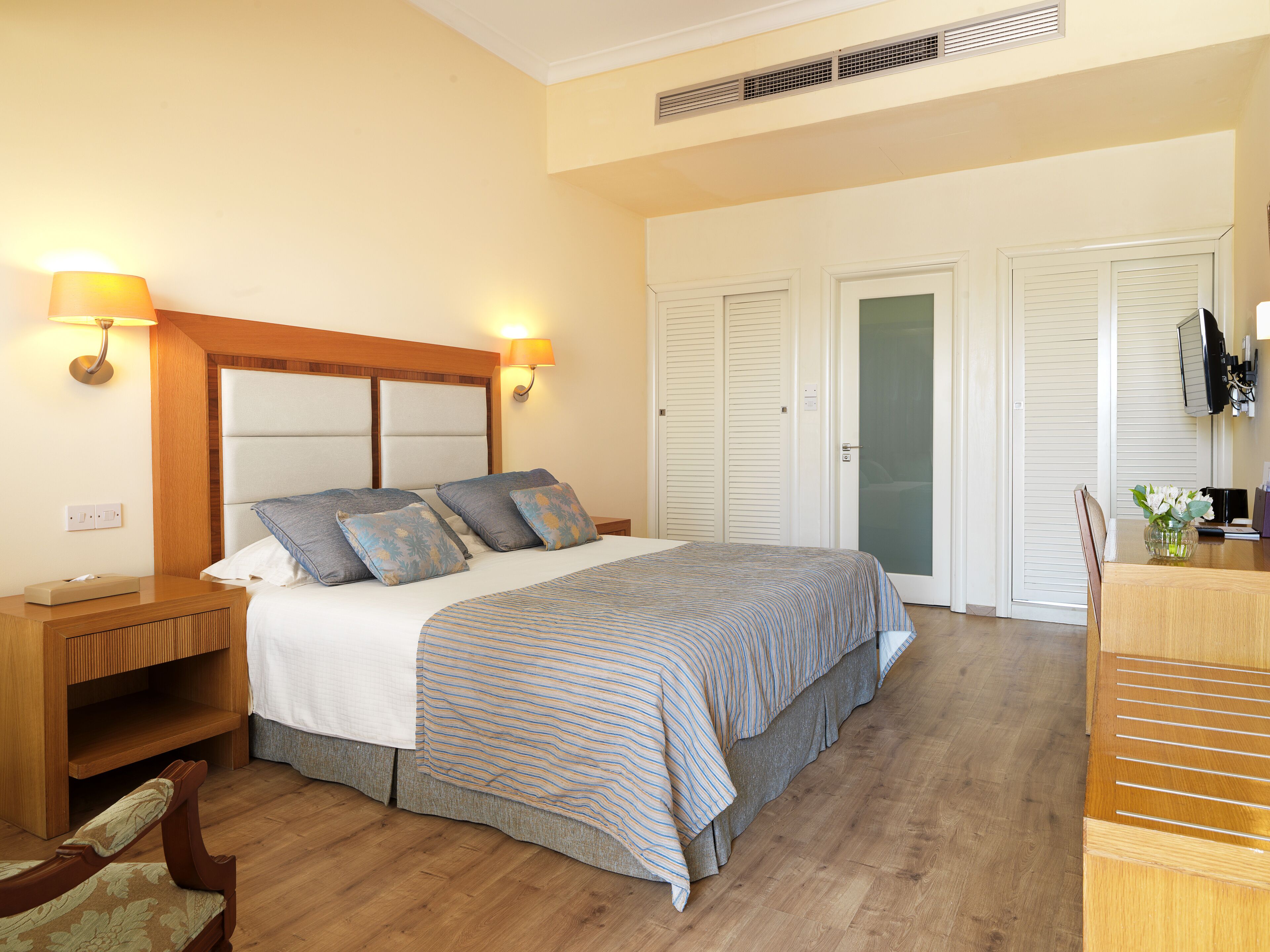 A hotel room with a bed, bedside tables, a TV, and a wardrobe.