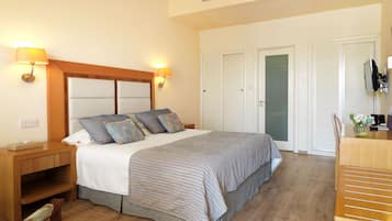 A hotel room with a bed, bedside tables, a TV, and a wardrobe.