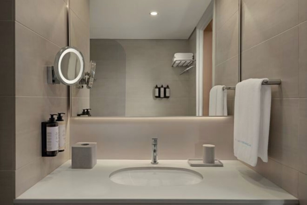 A modern bathroom with a large mirror, a sink, and a towel rack.
