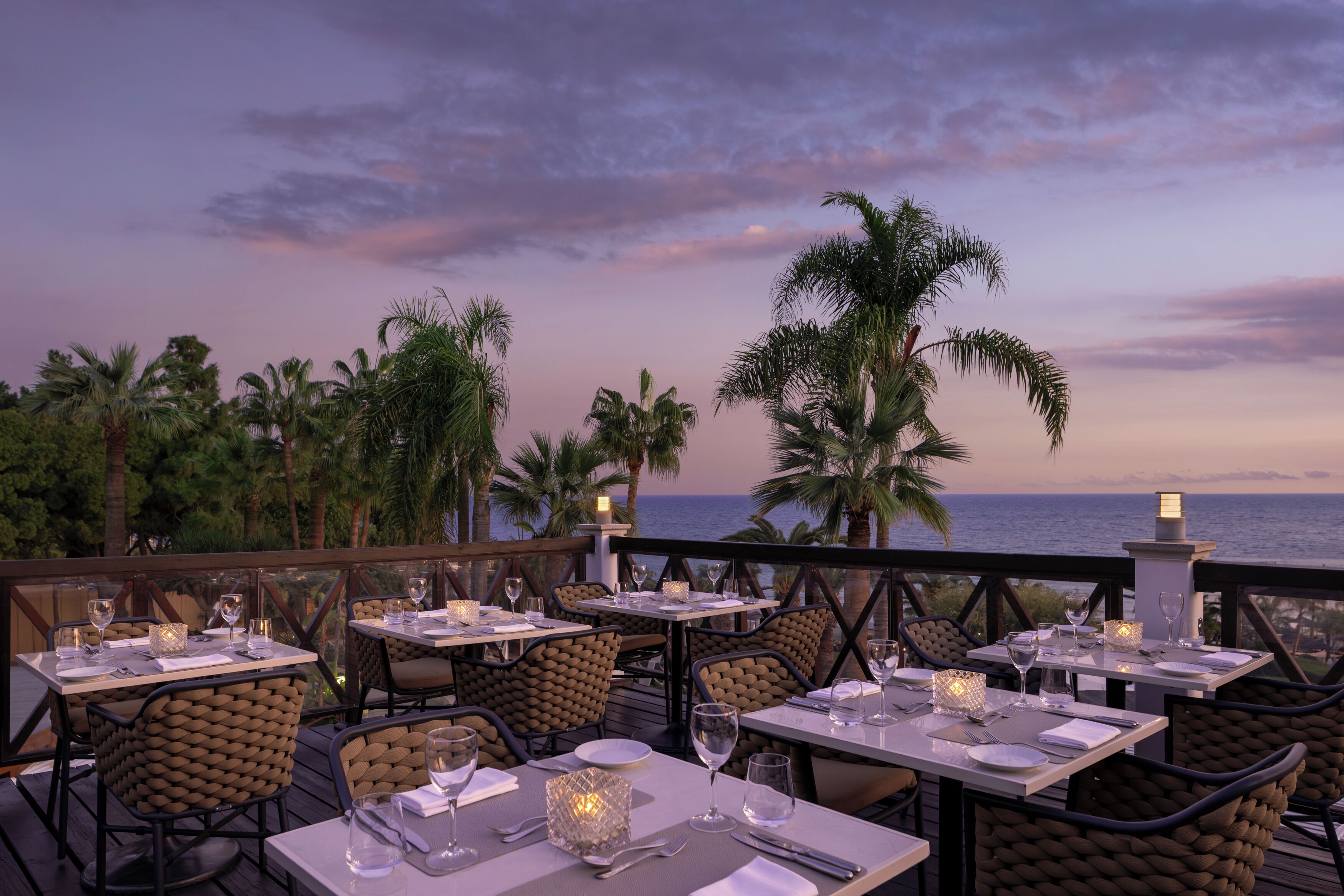 An outdoor dining area with tables and chairs, overlooking the ocean.