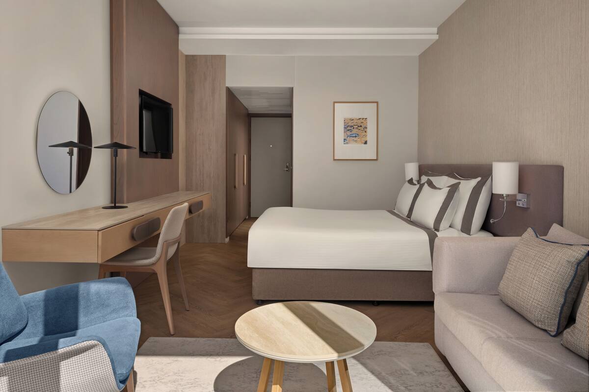 Una habitación de hotel moderna con una cama, un sofá, un escritorio y una silla.