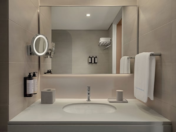 A modern bathroom with a large mirror, a sink, and a towel rack. - Mediterranean Beach Hotel (Limassol)