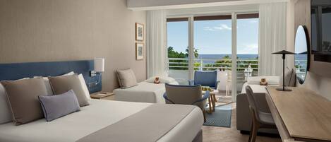 A hotel room with a bed, two bedside tables, a desk, a chair, a TV, and a balcony with a view of the ocean.