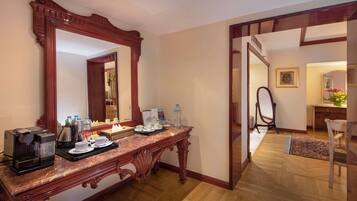Une chambre d’hôtel équipée d’une console en bois, d’une machine à café, de bouteilles d’eau et d’un miroir.