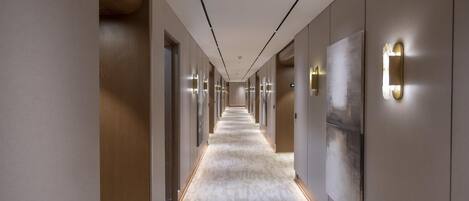 A long, narrow hallway with a patterned carpet, recessed lighting, and a modern design.