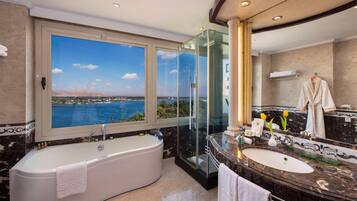 A luxurious bathroom with a large bathtub, a vanity with a mirror, and a view of a body of water.