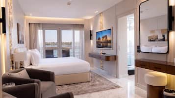 A modern hotel room with a large bed, a TV, a desk, and a bathroom.