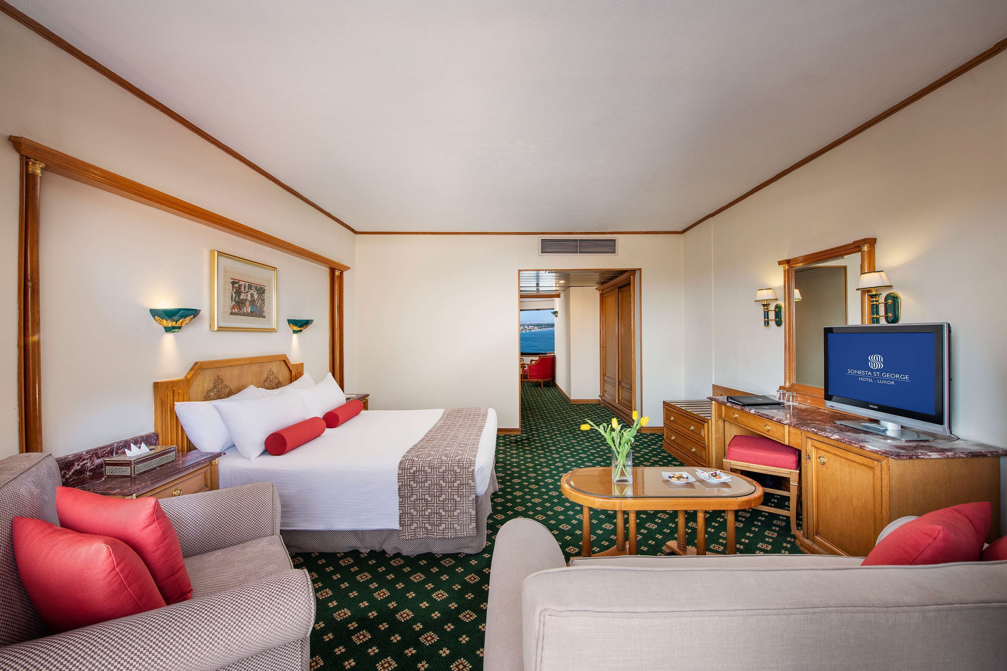 Une chambre d’hôtel avec un lit, un bureau, une télévision et une vue sur la mer.