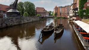 A river with boats, historic buildings, and a bridge. - DORMERO Hotel Bergström Lüneburg (Lueneburg)