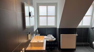 Une salle de bain moderne avec un grand miroir, un meuble-lavabo en bois, un évier et un porte-serviettes.
