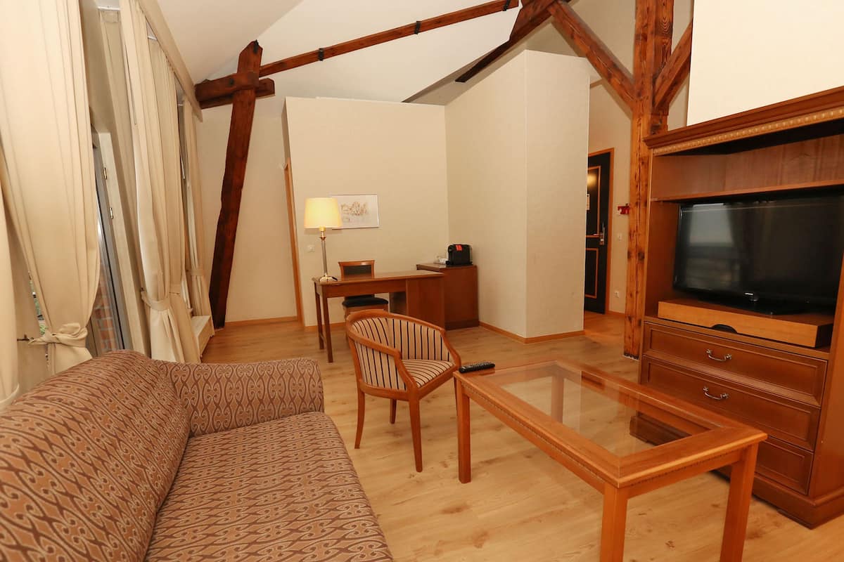Un salon avec un canapé, une table basse en bois, un téléviseur et un bureau avec une lampe.