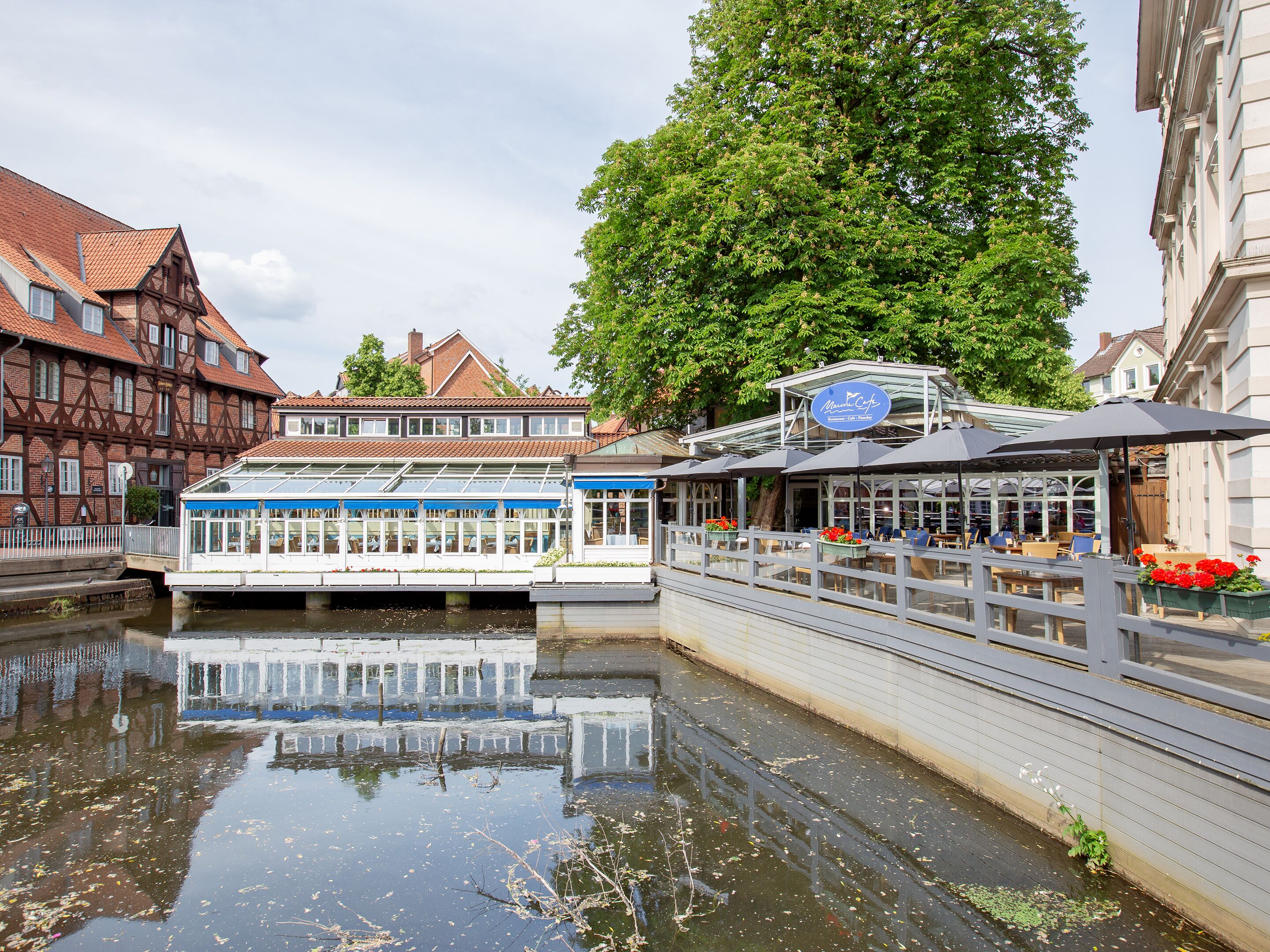 A river with a boat docked on the right, a bridge in the foreground, and buildings on the left.