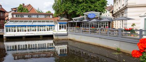 A riverside café with outdoor seating and a glass-roofed building.