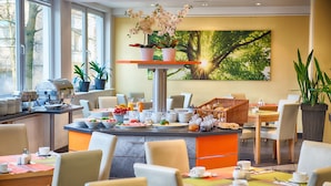 A well-lit breakfast area with a buffet setup, including various food items and a coffee station. - Enjoy Hotel Berlin City Messe (Berlin)