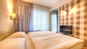 A hotel room with two beds, a television on a stand, and a checkered wall pattern. - Enjoy Hotel Berlin City Messe (Berlin)