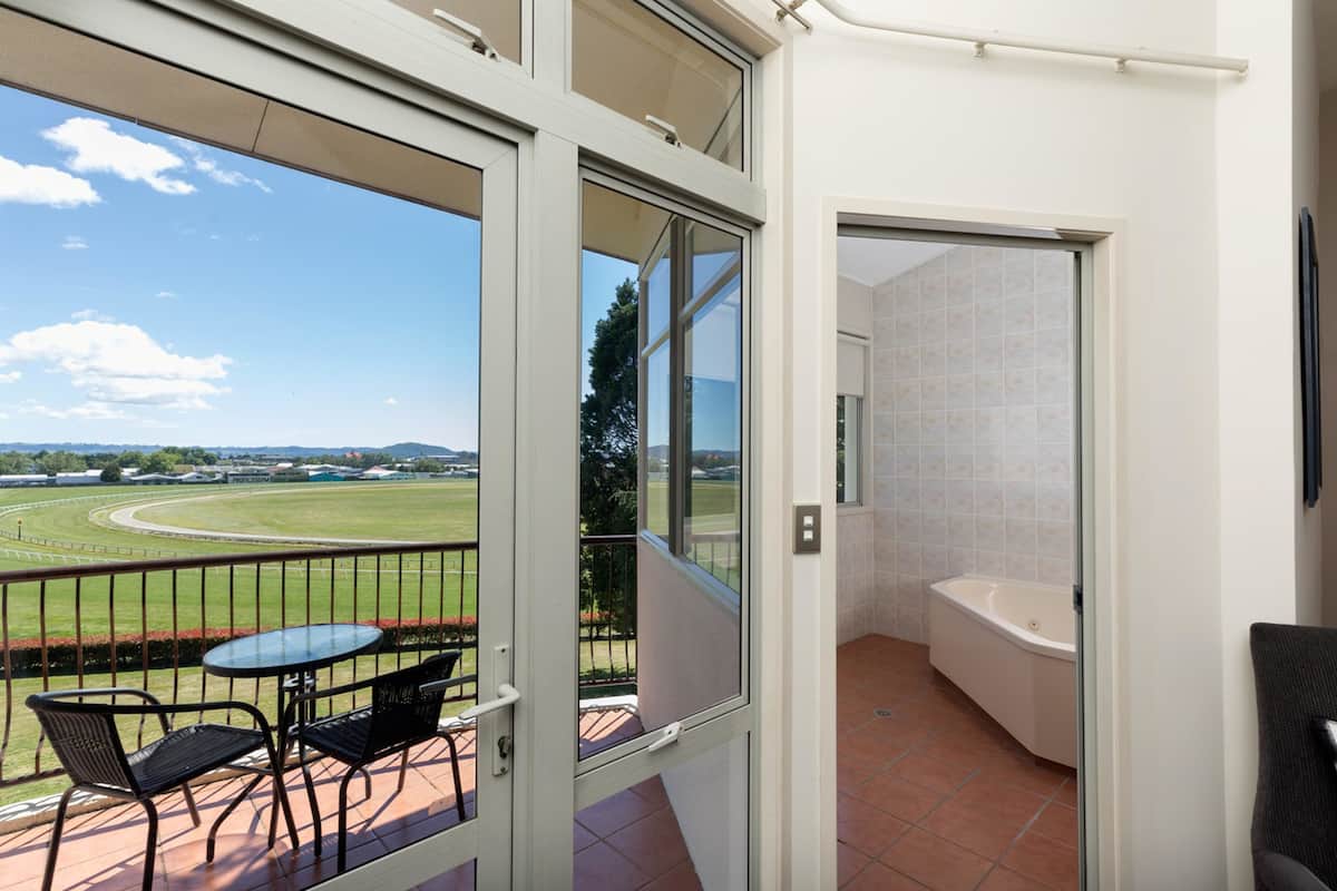 A balcony with a glass door leading to a bathroom, a small table, and chairs.