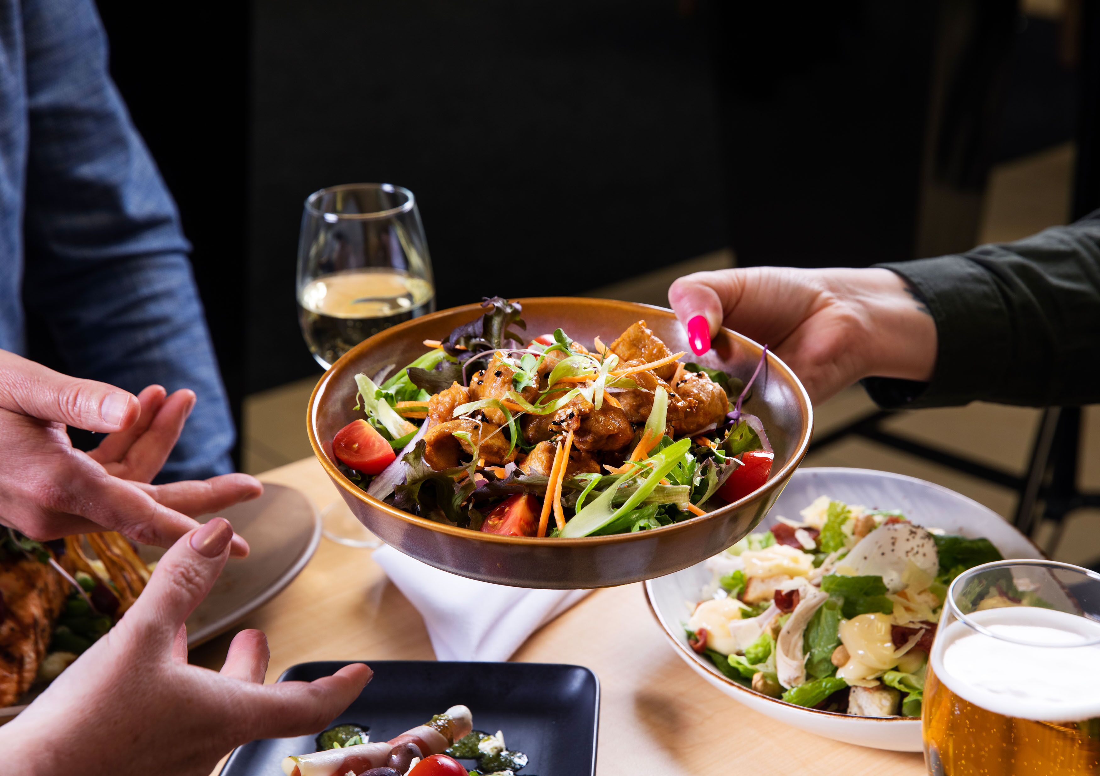 Un groupe de personnes est réuni autour d’une table pour partager un repas, avec différents plats et boissons.
