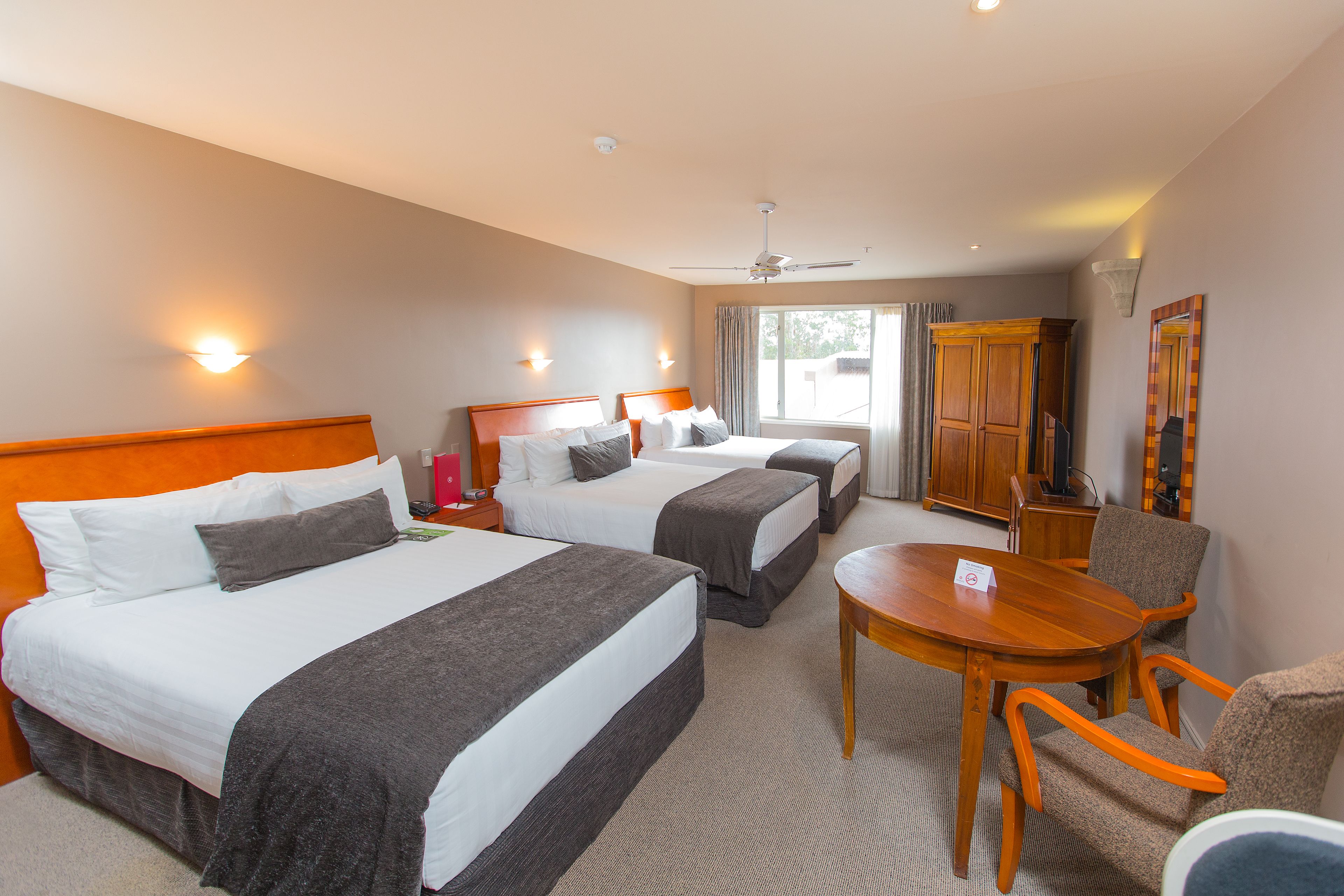 Een hotelkamer met drie bedden, een eettafel en een televisie.
