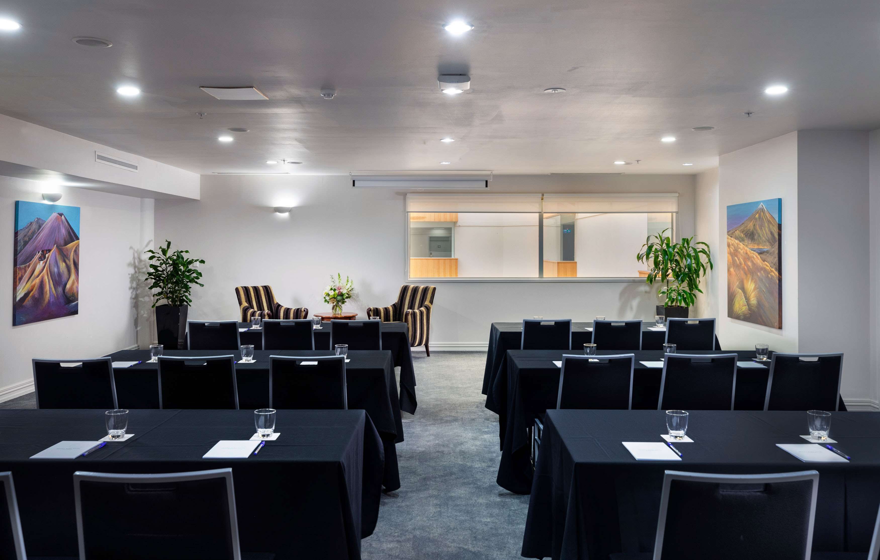 A conference room with tables, chairs, and potted plants.