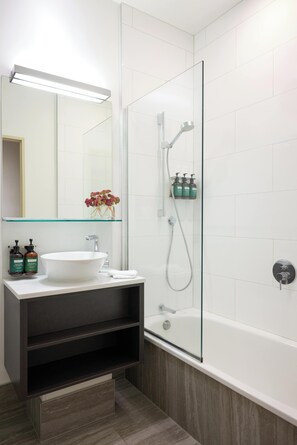 A modern bathroom with a glass-enclosed shower, a white sink, and a mirror above it. - Adina CityLife Wellington (Wellington)