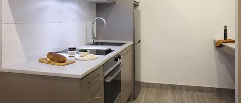 A modern kitchen with a stainless steel sink, a built-in oven, and a microwave.