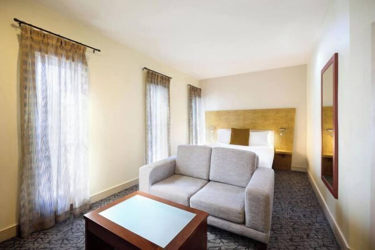 Una camera d'albergo con divano, un tavolino, un letto, una testiera e un comodino.