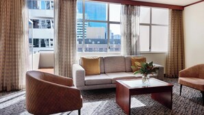 A modern hotel room with a large window, a sofa, two armchairs, a coffee table, and a patterned carpet. - Adina CityLife Wellington (Wellington)