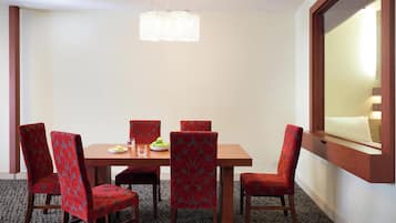 Un coin repas avec une table en bois, six chaises rouges à revêtement rembourré, un lustre et une fenêtre donnant sur un paysage agréable.