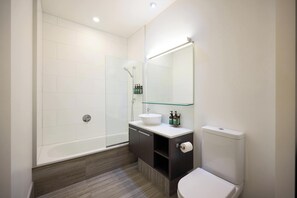 Un baño moderno con cabina de ducha de vidrio, un lavabo blanco, un inodoro y un espejo sobre el lavabo.