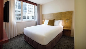 A hotel room with a large bed, a TV, a window with curtains, and a wooden headboard. - Adina CityLife Wellington (Wellington)