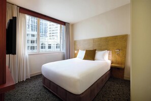 A hotel room with a large bed, a TV, a window with curtains, and a wooden headboard. - Adina CityLife Wellington (Wellington)