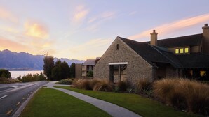 A modern stone house with a stone facade, a sloped roof, and a view of mountains in the background. - Rendezvous Heritage Hotel Queenstown (Queenstown)