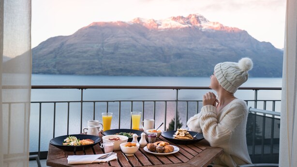 A balcony with a table set for breakfast overlooking a mountain and lake. - Rendezvous Heritage Hotel Queenstown (Queenstown)