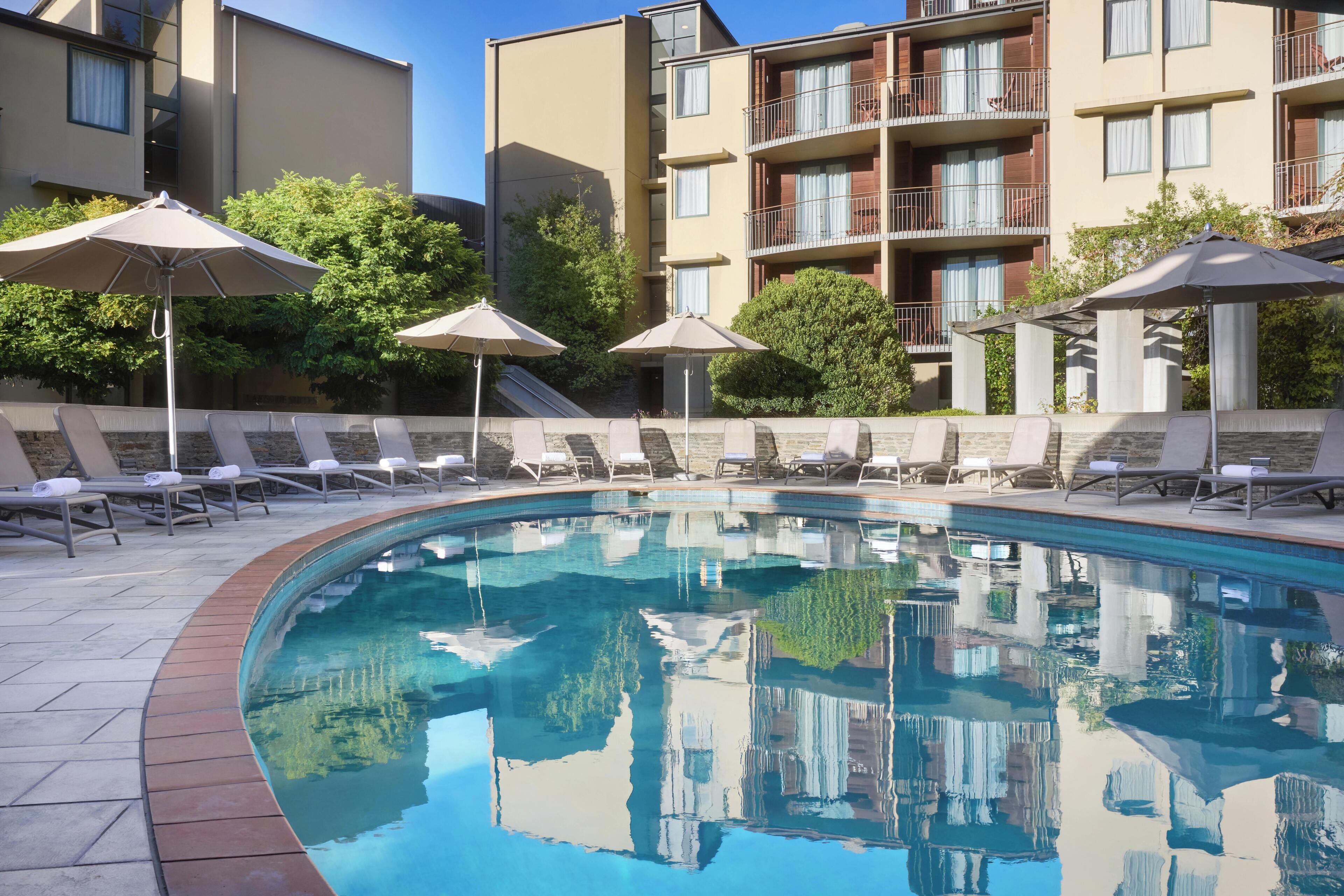 Una piscina techada, una piscina al aire libre, sombrillas