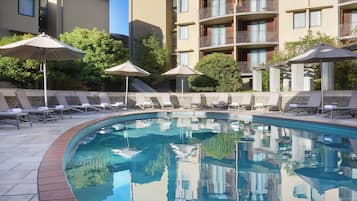 Una piscina techada, una piscina al aire libre, sombrillas