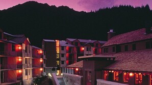 A hotel with a swimming pool, outdoor seating, and a mountain backdrop. - Rendezvous Heritage Hotel Queenstown (Queenstown)
