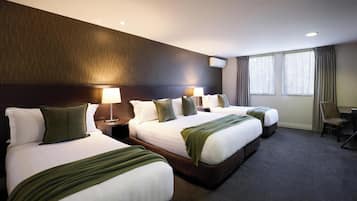 A hotel room with three beds, a desk, and a chair.