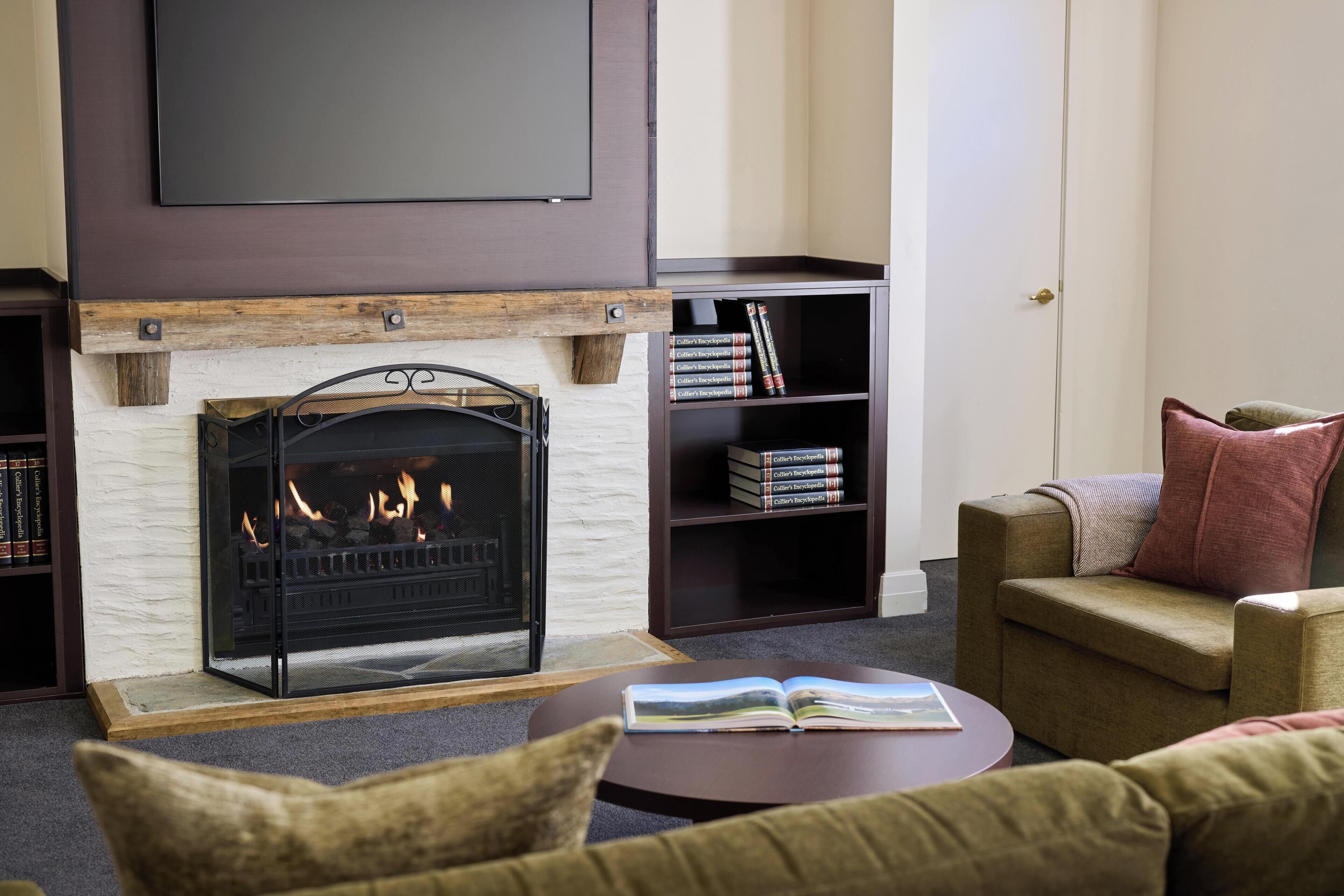 Una sala de estar con chimenea, un sofá, una mesa de centro y una estantería.