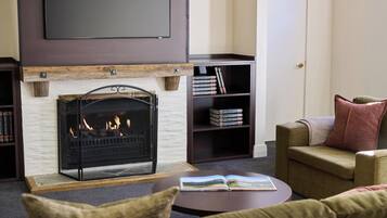 Una sala de estar con chimenea, un sofá, una mesa de centro y una estantería.