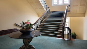 Een statige trap met een leuning, een potplant en een tafel in een ruime binnenruimte.