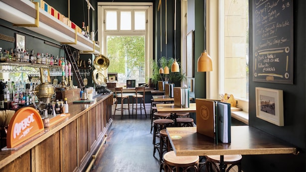 Een barruimte met houten meubels, flessenkasten en een krijtbordmenu.
