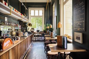 Una zona de bar con muebles de madera, estanterías llenas de botellas y un menú en la pizarra.