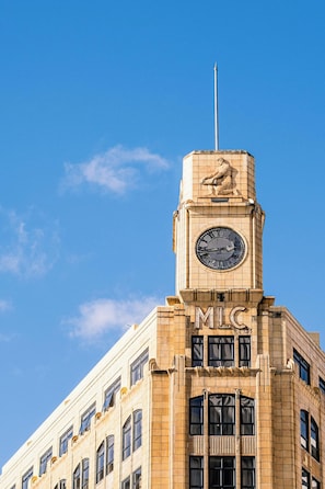 A building with a clock tower and the letters "MIC" on the facade. - Quest Wellington (Wellington)
