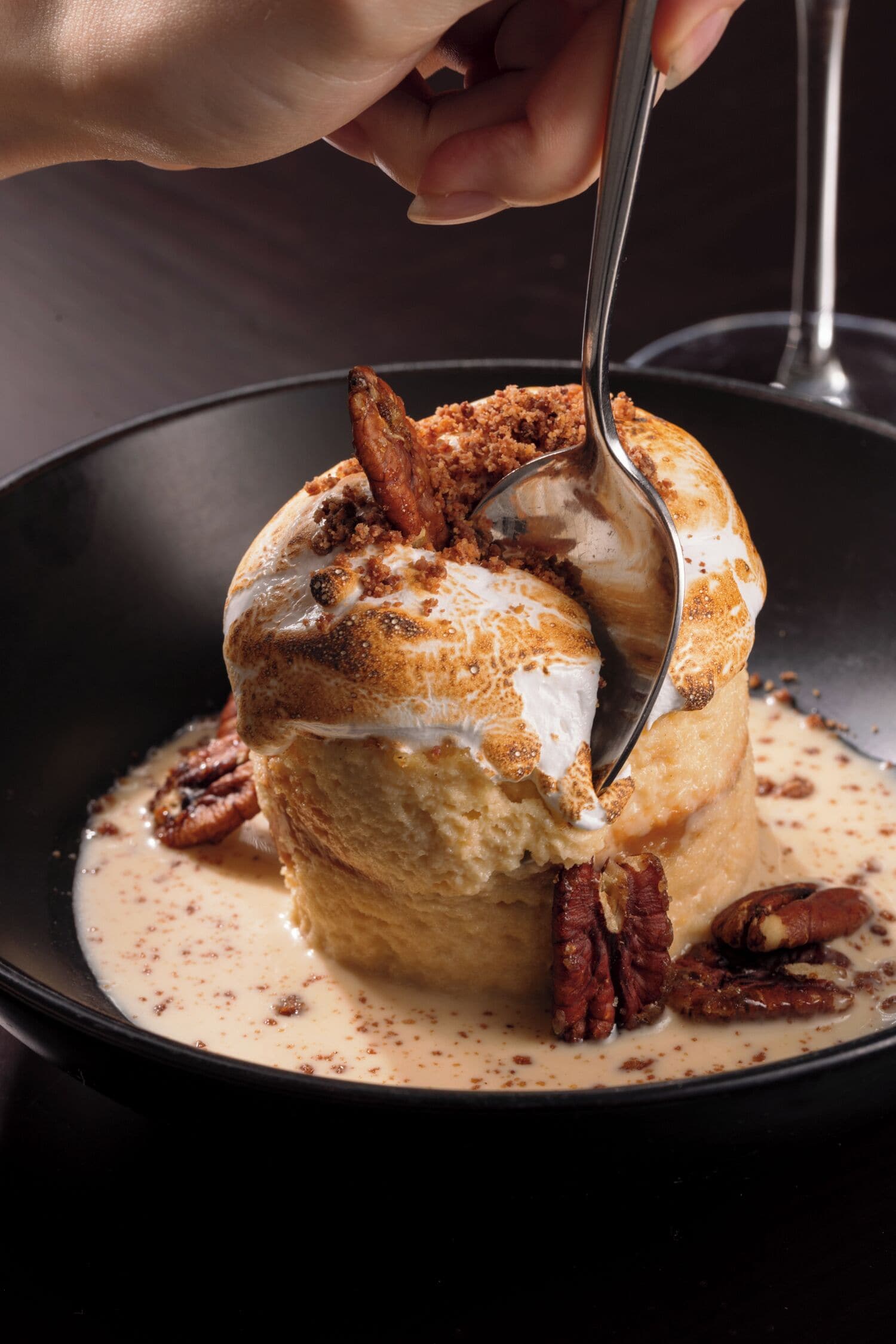 A dessert with a scoop of ice cream on top, served in a black bowl.