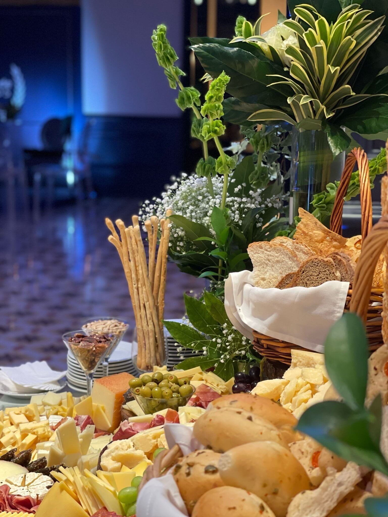 A table with a variety of cheeses, breads, olives, and nuts.