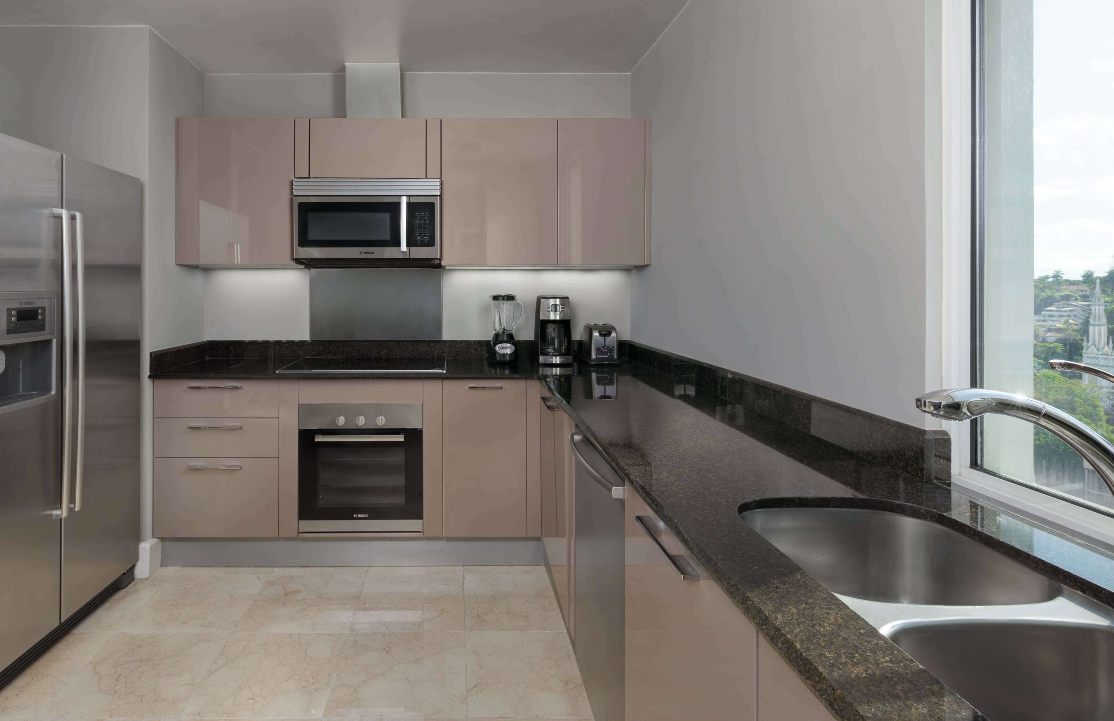 A modern kitchen with stainless steel appliances, a large window, and a view of a cityscape.