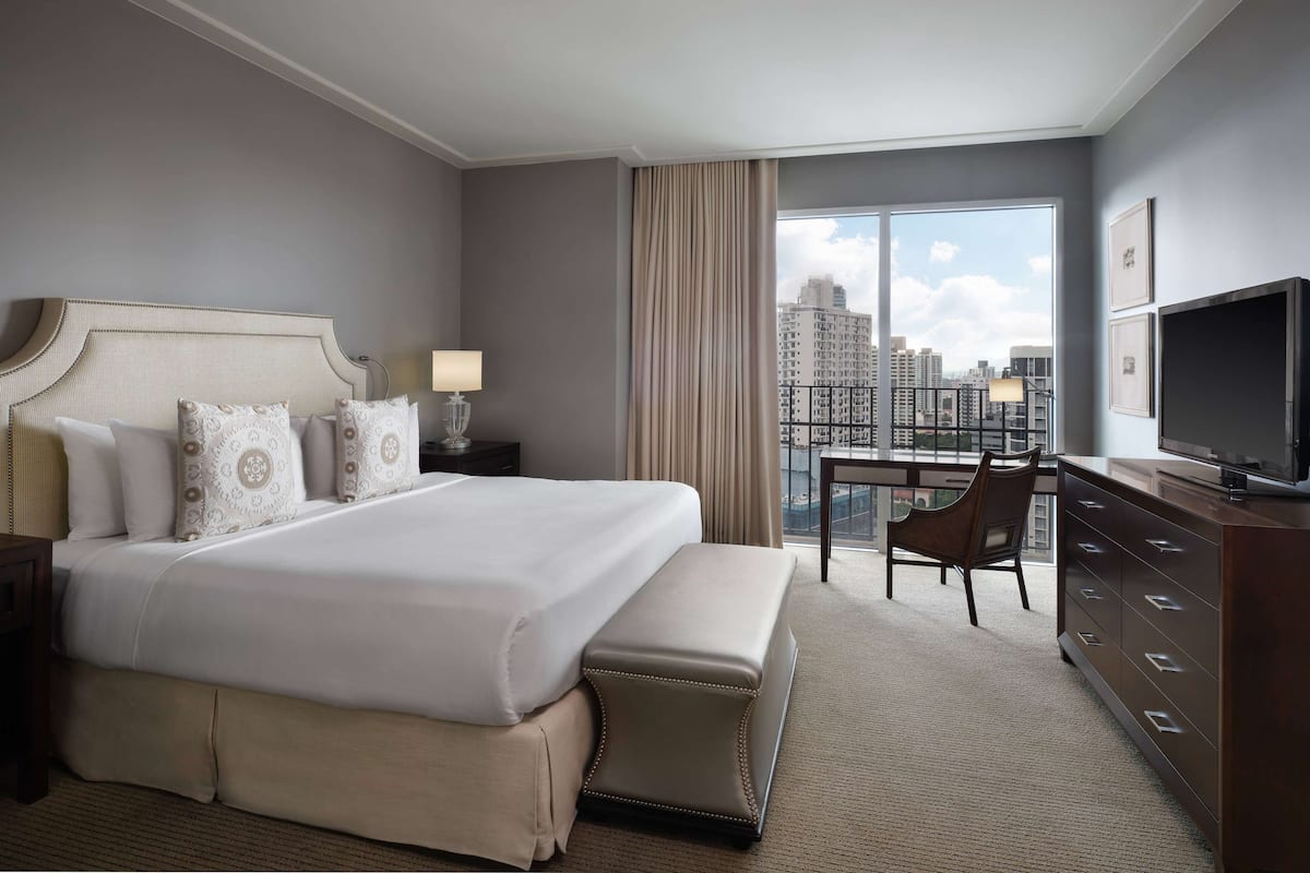 Een hotelkamer met een groot bed, een bureau, een televisie en uitzicht op de stad.
