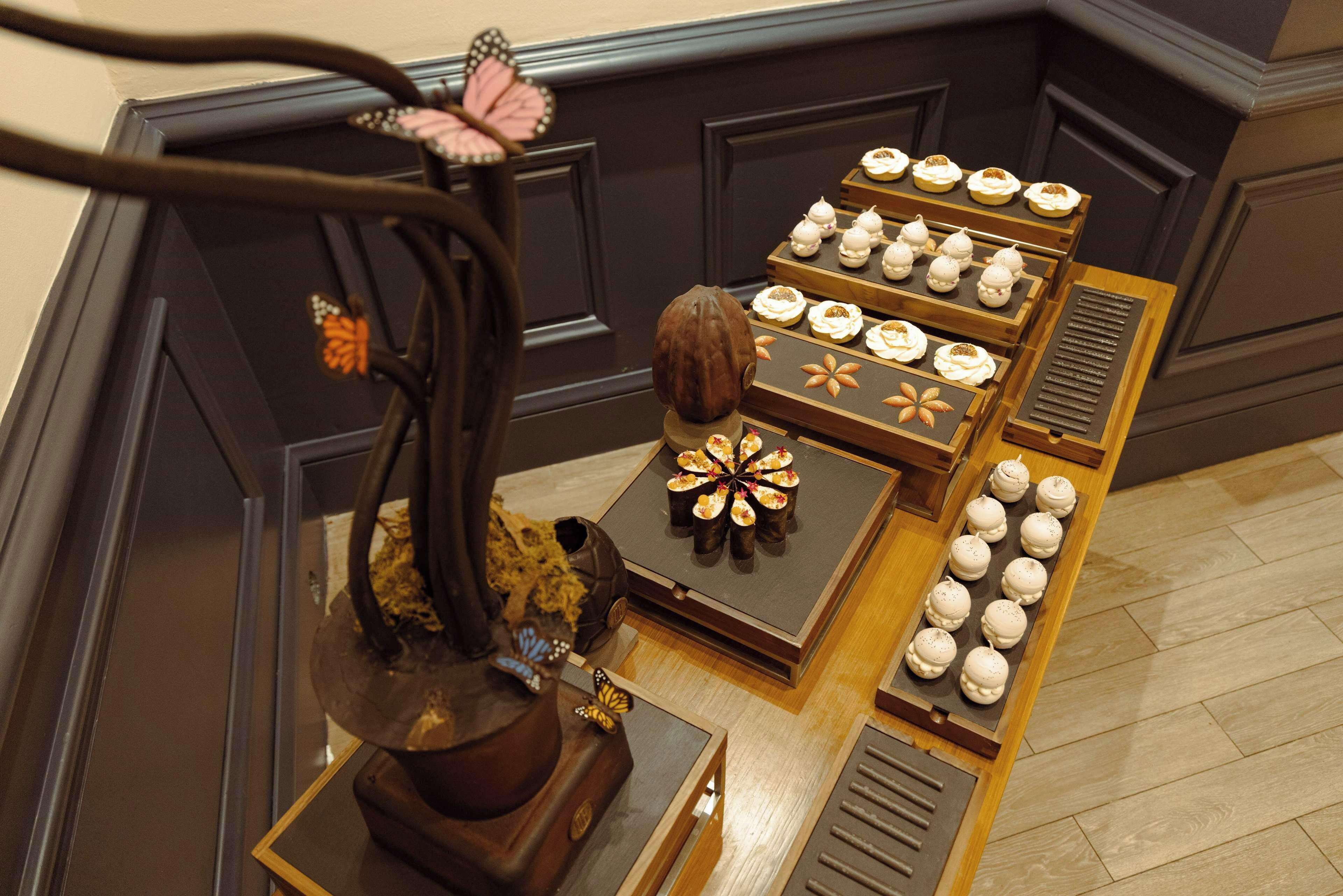 A display of pastries on a wooden table with decorative elements like a tree and butterfly.