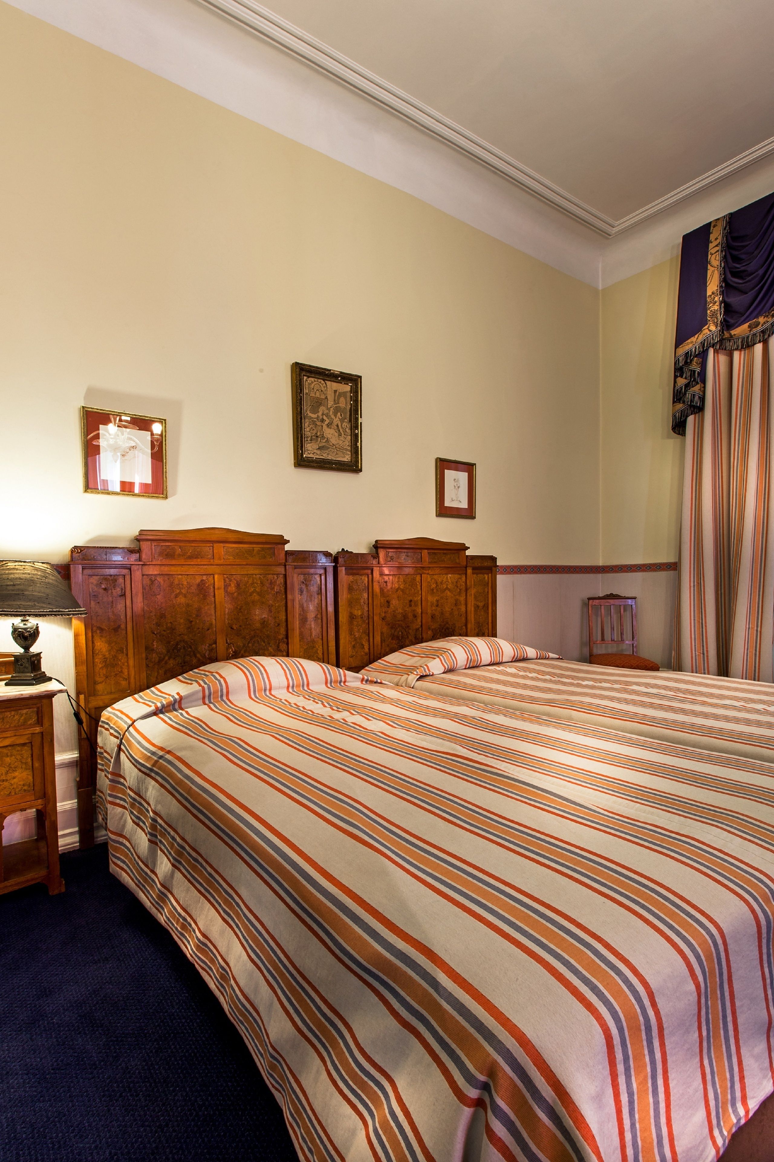 A bedroom with a large bed, wooden headboard, a nightstand with a lamp, and a small table with a framed picture.